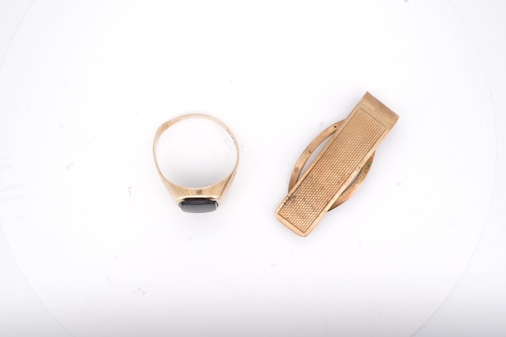 A 1980's 9ct gold tie clip, 39mm and a similar 9ct gold and black onyx set signet ring, gross weight 10 grams.